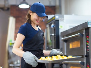 Baker taking buns out of the oven inside a catering kitchen