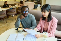 Managers analyzing labor costs sitting in a café, with drinks and notes on the table