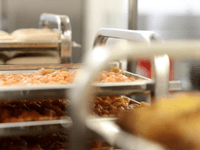 This is an image of food preparation within a commercial kitchen environment, likely a ghost kitchen.