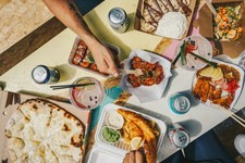The scene suggests a casual meal shared by several people, likely featuring food ordered from multiple restaurants, which is common with "ghost kitchen" or delivery-focused models.