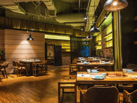 
The image depicts the dimly lit and warmly decorated interior of a modern restaurant or dining establishment.