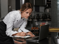 The image shows a female chef or restaurant professional working in a commercial kitchen setting.
