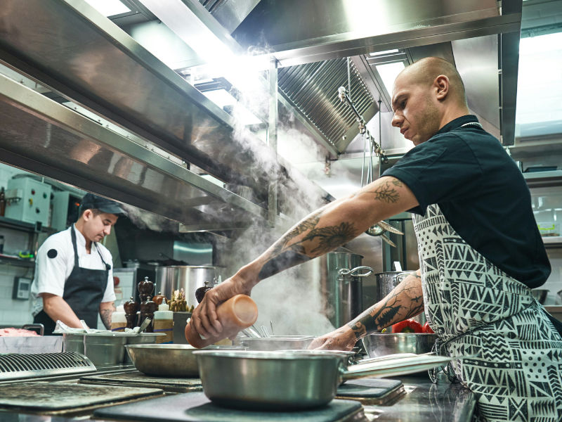 This is a dynamic photograph captured inside a busy, professional kitchen environment.