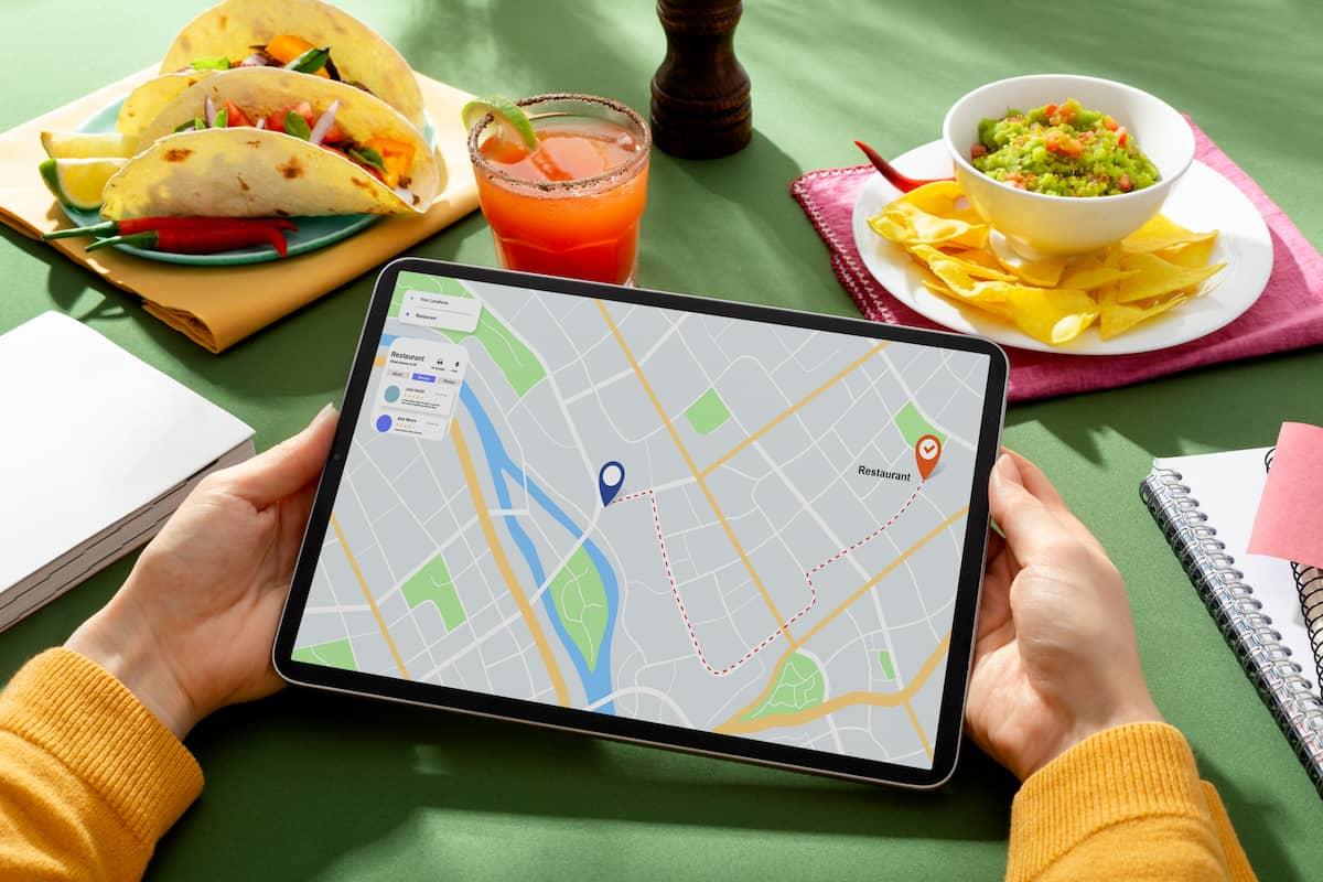 Person holding tablet with a map and route, illustrating restaurant location strategy​ for food delivery.