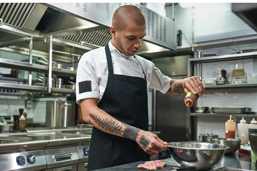 The image shows a chef in a professional setting, which appears to be a restaurant or commercial kitchen.