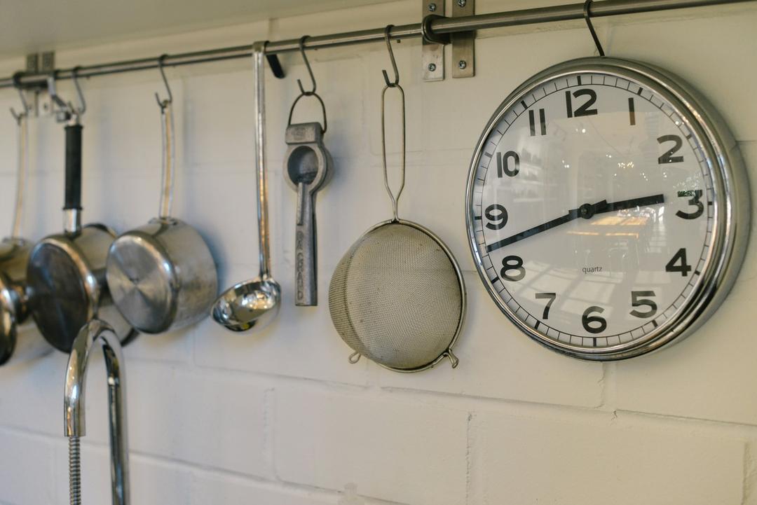 This is a close-up, horizontal photograph of a kitchen wall showing a storage system and a clock.